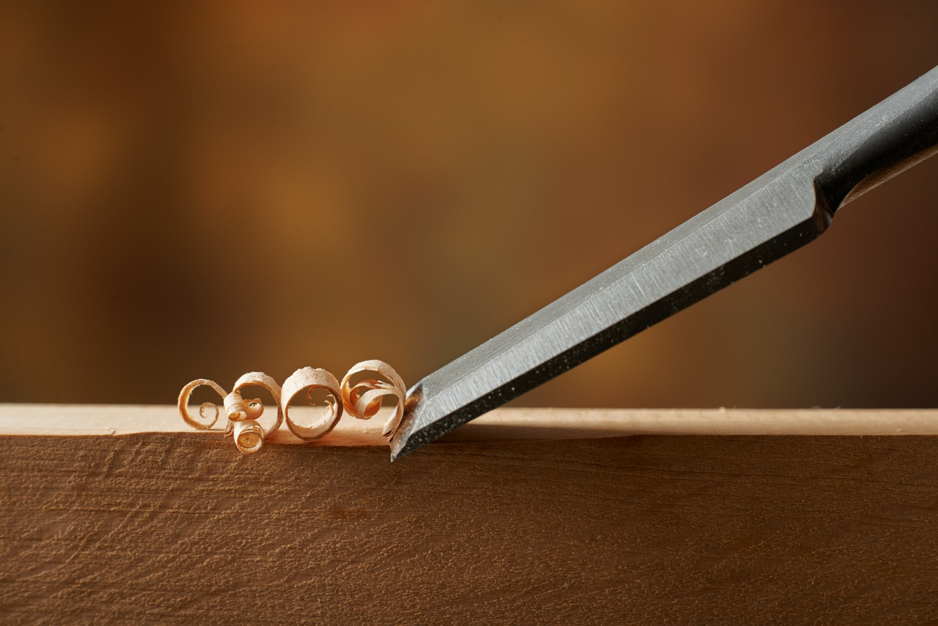 Carving wood with a chisel, a woodworking tool.